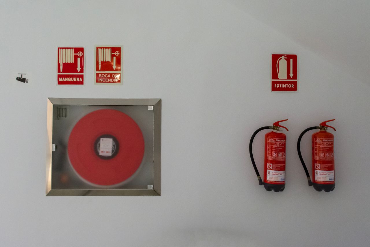 Mastering the First Impression: Your intriguing post title goes here Fire safety setup with extinguishers and hose reel on a white wall for emergency preparedness.