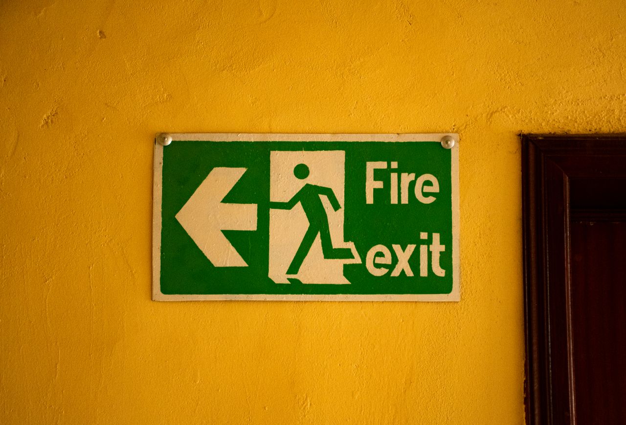 Fire exit sign on a yellow wall, indicating safety and emergency exit direction.